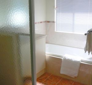 Geraldton Luxury Vacation Home with free Streaming في جيرالدتون: حمام مع دش وحوض استحمام ومغسلة