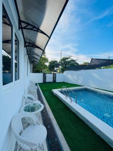 a swimming pool with chairs and a table next to a swimming pool at Impiani Chalet with Private Pool in Kuala Terengganu