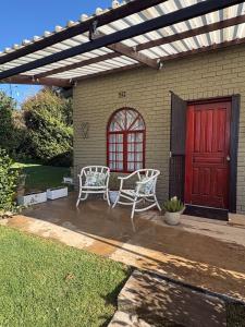two white chairs on a patio with a red door at 19 on Amber in Ugie +1 photo