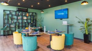 a dining room with tables and chairs and a tv at Campanile PRIME - Lyon Meyzieu Eurexpo Arena Stadium in Meyzieu