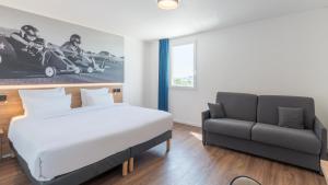 a bedroom with a bed and a couch at Campanile PRIME - Lyon Meyzieu Eurexpo Arena Stadium in Meyzieu