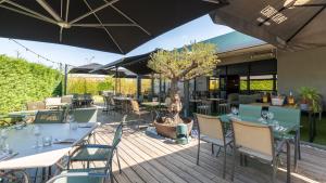an outdoor patio with tables and chairs and a tree at Campanile PRIME - Lyon Meyzieu Eurexpo Arena Stadium in Meyzieu
