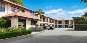 eine Reihe von Gebäuden mit Autos auf einem Parkplatz in der Unterkunft Randolph Motel Apartments in Christchurch