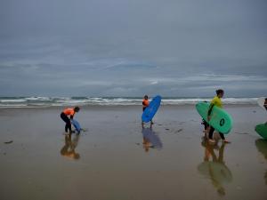 a group of people standing on the beach with surfboards at D'Ici ou D'ailleurs in Barneville-Carteret +6 photos