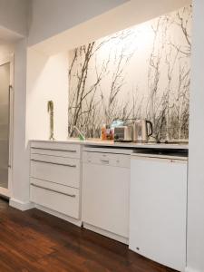 a kitchen with white cabinets and a painting on the wall at Cape Town Panorama Luxe Suite in Cape Town