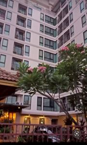 a large white building with palm trees in front of it at Baan Tanwa - MRT Ratchadapisek Exit 1 or 2 in Bangkok