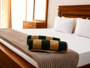 a bed with a green and brown blanket on it at RT Point Gombamiya Hotel Kandy in Huluganga