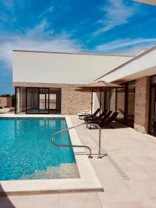a swimming pool with two chairs and an umbrella at Soline Rocks Resort in Mlini