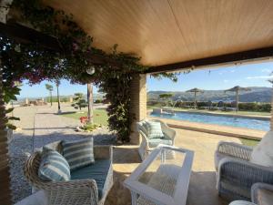 a patio with wicker chairs and a swimming pool at Casa Puerta Azul By Solymar Properties in Almáchar