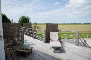 a chair sitting on top of a wooden deck with a field at Loft in de Polder in Grootschermer