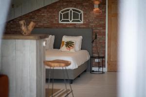 a bedroom with a bed and a brick wall at Loft in de Polder in Grootschermer