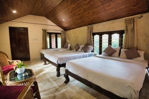 a room with three beds and a table and chairs at Coffee County in Srimangala