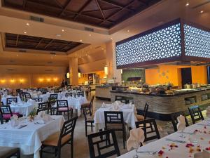 a restaurant with white tables and chairs and a kitchen at Alhambra Thalasso in Hammamet