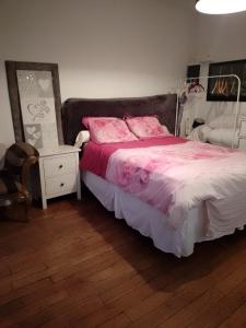 a bedroom with a bed with pink sheets and a night stand at Studio pied du métro Neuilly Paris La Défense pour 3 maxi in Neuilly-sur-Seine