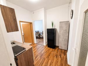a kitchen with a black refrigerator and a wooden floor at BaB Hotels and Apartments Apolo 3 in Chemnitz