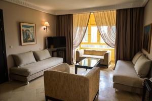 a living room with a couch and chairs and a tv at Alhambra Thalasso in Hammamet