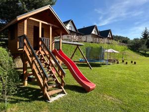 a playground with a slide in front of a house at Bieszczadzki Bohater Domki 533-502-137 in Polańczyk