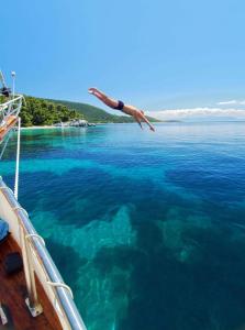 a person jumping into the water from a boat at Blue Green Bay in Panormos Skopelos