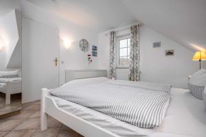 a white bedroom with a bed and a window at Seestrasse Haus 15 in Zingst