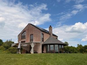 een bakstenen huis met een prieel op een veld bij Rotonde in Somme-Leuze