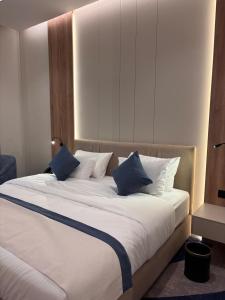 a large bed with blue and white pillows on it at Voyage Expo Suites in Riyadh +21 photos