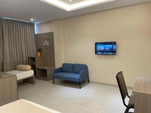 a hospital room with a blue chair and a tv on the wall at Raghav Residency in Vellore