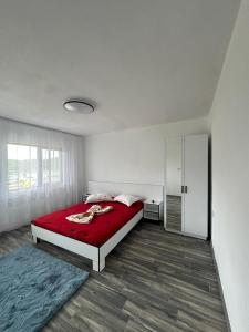 a white bedroom with a red bed and a door at Casa De Vacanță Maga Dubova in Dubova +32 photos