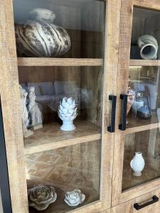a wooden cabinet filled with vases and vases at Sunshine centrum in Koksijde