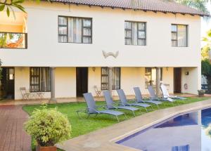 a house with a row of chairs by a pool at Ponciana Superior Guesthouse in Hartbeespoort