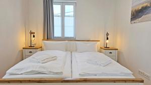 a bedroom with a bed with white sheets and pillows at Villa Küstenperle, Meerblick-Appartements in Sassnitz
