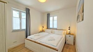 a bedroom with a white bed with two windows at Villa Küstenperle, Meerblick-Appartements in Sassnitz