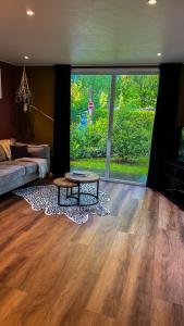 a living room with a table and a large window at Panterhuis Leo l Tiny House l Buitenbad, airco, speeltuin, bostuin in Epe