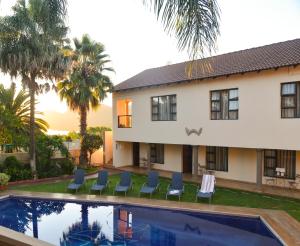 a house with a swimming pool in front of a house at Ponciana Superior Guesthouse in Hartbeespoort