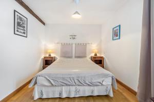 a bedroom with a white bed and two night stands at Gite Périgourdin - 2 Chambres in Saint-Geniès