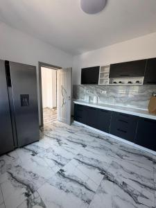 a kitchen with black cabinets and a marble floor at Ionela in Năvodari
