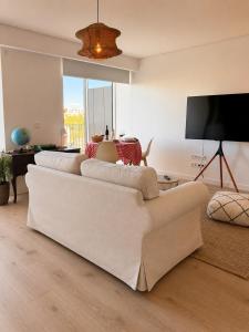 a living room with a white couch and a flat screen tv at Home2830 in Barreiro
