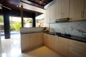 a kitchen with wooden cabinets and marble counter tops at The Nakula Villas in Legian