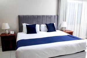 a bedroom with a large bed with blue pillows at Kentucky Hotel in Harare