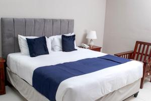 a large bed with blue and white sheets and pillows at Kentucky Hotel in Harare +6 photos