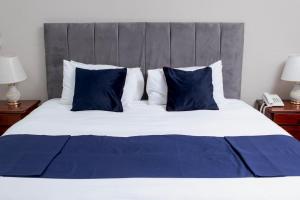 a large bed with blue and white pillows at Kentucky Hotel in Harare