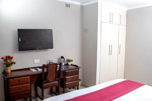 a bedroom with a desk and a bed and a tv at Kentucky Hotel in Harare