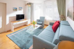 a living room with a blue couch and two chairs at Kleine Möwe 08 in Norderney