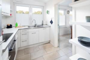 a white kitchen with a sink and two windows at Seehaus 48 in Norderney +20 photos