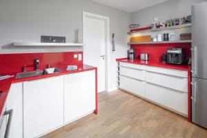 a kitchen with white cabinets and red counter tops at Mühlenloft in Norderney +12 photos