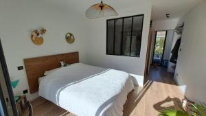 a bedroom with a white bed and a mirror at Maison GINKGO in Hourtin