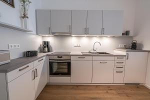 a white kitchen with white cabinets and a sink at Meergenuss in Norderney