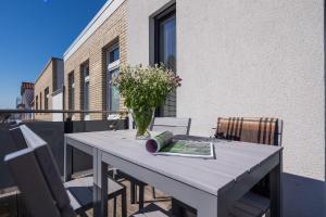 a table with a vase of flowers on a balcony at Robbenloft in Norderney
