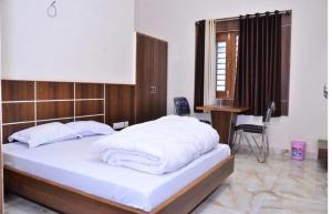 a bedroom with a large white bed with a wooden headboard at Hotel Rama palace in Mathura
