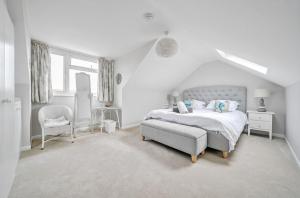 a white bedroom with a bed and a chair at Number Twenty Four in West Wittering