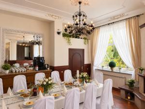 a dining room with a table with white chairs and a chandelier at Adria in Bieruń Nowy